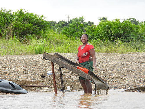 Mujer minera artesanal del Chocó trabajando con canalón a orillas del río